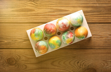 Colored Easter eggs in tray on wooden table