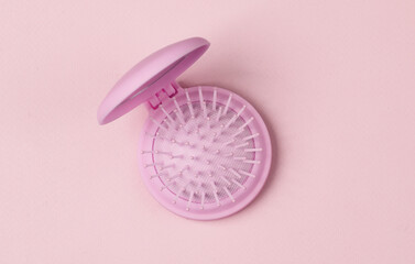 Beauty organizer folding hair brush on pink background. Top view