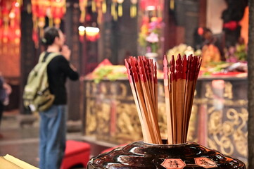 Obraz premium Taiwan - Mar 02, 2025: Detailed view of cylindrical fortune stick holder in a Taiwanese temple. The shallow depth of field reveals a woman performing traditional prayers seeking divine intervention.