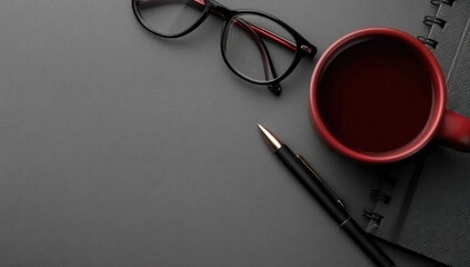 A cup of coffee, pen and glasses on a table