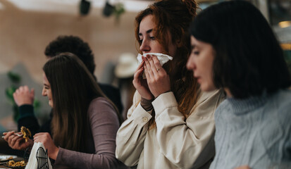 A group of friends expressing emotions while dining together in a relaxed indoor setting. The atmosphere conveys companionship, laughter, and good food in a casual environment.
