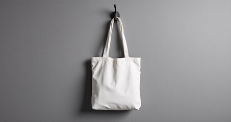 Totebag hanging on monochrome grey wall, clean and symmetrical setup with soft studio lighting. Great for mockup or product branding presentation.