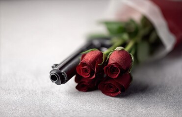 A bunch of red roses sitting next to a gun