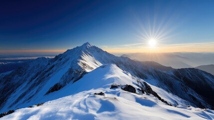Fototapeta premium Snowy mountain peak at sunrise. Vast snow-covered mountain range under a clear sky. Sunlight radiates outward from the setting sun