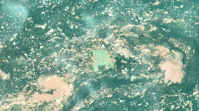 This aerial shot showcases the disturbing reality of ocean pollution, with large areas of water tainted by plastic and waste, urging immediate action to protect marine life.
