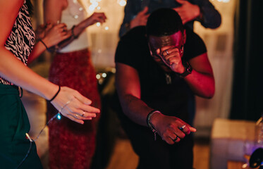 Friends enjoying a lively birthday celebration at home, with music, dancing, and happiness. The...