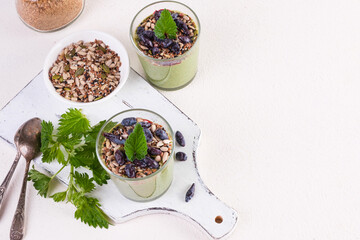 Healthy eating, lifestyle, veganism, alkaline diet, vegetarian concept. Green smoothies from nettle and yogurt, with honey, bran, seed mix and honeysuckle. Garnished with a mint leaf