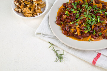 Red beans in tomato sauce with green onions and walnuts. Lenten vegetarian food. Copy space