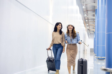 Two Happy Asian Female Friends Travelling Together. Happy asian woman passenger traveler waiting for departure with suitcase at modern airport terminal