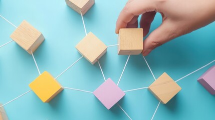 Hand connecting wooden blocks with string on blue background