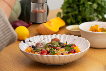 Fresh warm autumn salad with pumpkin and chickpeas is salted with pink Himalayan salt