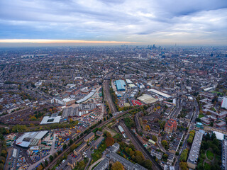 London's Urban Expanse : Suburbs to Skyline at Dusk. Dramatic aerial photograph capturing London's vast urban landscape from suburban neighborhoods to distant city skyline under moody clouds horizon.