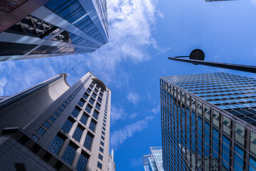 Obraz premium Modern skyscrapers with reflective glass facades under a blue sky. Urban architecture, business district, financial center, corporate growth, and city development