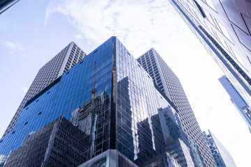 Obraz premium Modern skyscrapers with reflective glass facades under a blue sky. Urban architecture, business district, financial center, corporate growth, and city development