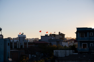 Albanian flags on rooftops at sunset