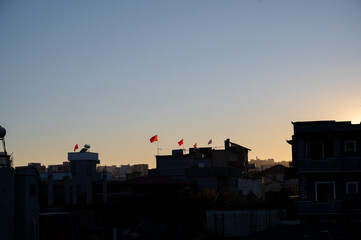 Naklejka premium Albanian flags on rooftops at sunset