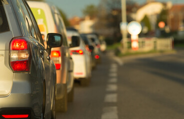 A long and linedup queue of numerous cars on a bustling city street during the beautiful golden hour of sunset