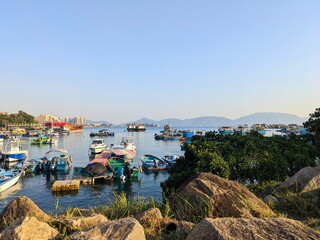 Colourful fishing boats anchored in the tranquil Castle Peak Bay under clear blue sky