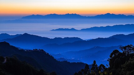 Fototapeta premium Misty mountain range at sunrise. Layers of blue mountains covered in morning mist