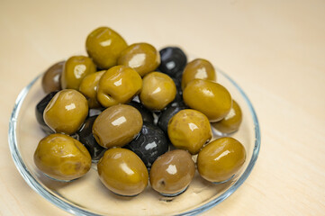 Black fermented olives and green olives preserved in close-up view on a bowl.