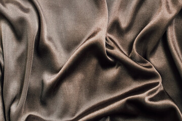 Soft brown fabric draped elegantly on a surface creating beautiful textures and shadows