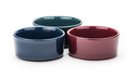 Ceramic pet food bowls in navy, teal, and burgundy on white background.