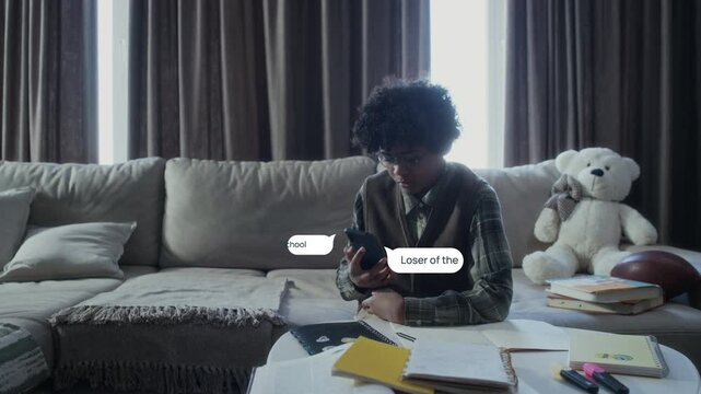 Medium shot of teenage black boy sitting at home, doing homework, with VFX of vile messages from online abuser popping up around him. Boy slamming phone down and weeping desperately