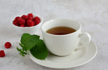 A cup of raspberry tea with fresh raspberries and mint