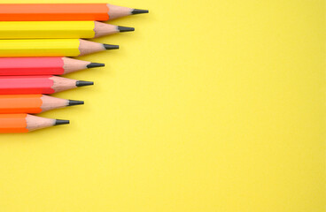 Set of sharpened colorful pencils arranged in a row on vivid yellow background. Ideal for school projects, creative back to school banners, kids' education visuals and print materials.