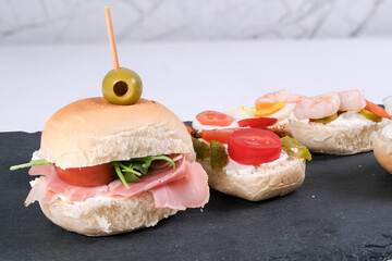 panino in primo piano su tagliere in pietra e tartine in secondo piano