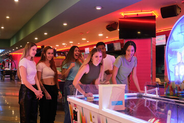 Group of young people enjoying a game of air hockey in vibrant arcade