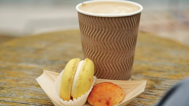 French dessert and a disposable cup of coffee to go.
Takeaway coffee and lemon macaroon close-up.
Sweet dessert with lemon and cappuccino.
Dessert in a cafe.
A sip in a restaurant and dessert