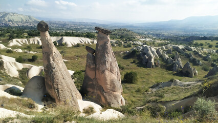 Unique rock formations rise majestically in the valley under the bright sky of Cappadocia, showcasing the natural beauty and geological wonders of Turkey.