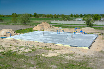 Budowa domu, pielęgnacja świeżej płyty fundamentowej poprzez zraszanie betonu wodą © gpmax