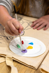 Inclusive art class for children with special needs, close-up of hand painting. Child painting on textile bag during inclusive art activity therapeutic activity supports sensory integration.  