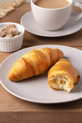 Freshly baked croissants served with a hot cup of coffee on a wooden table in a cozy setting