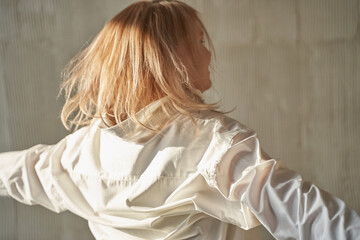 Young caucasian female joyfully twirling in a white shirt with blurred background impression.