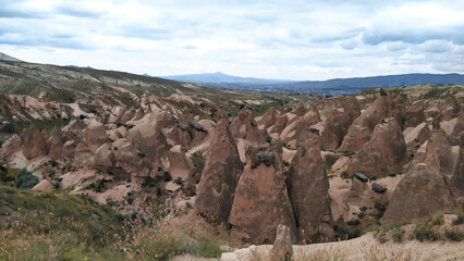 Bizarre rock formations in the valley of Cappadocia against the cloudy sky in a picturesque landscape, showcasing the natural beauty and geological wonders. Turkey nature exploration concept.