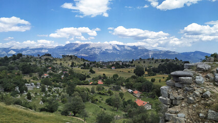 Scenic panoramic view of lush green hills and distant mountains under a bright blue sky with fluffy clouds showcasing natural beauty and tranquility concept