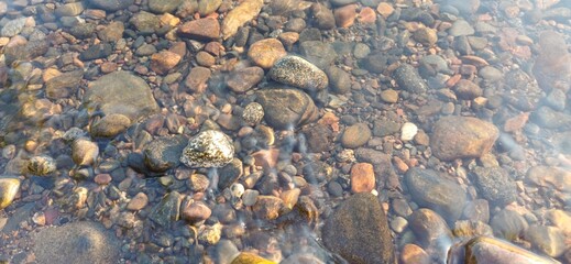 Calm riverbed with smooth pebbles and clear water during a sunny afternoon in nature