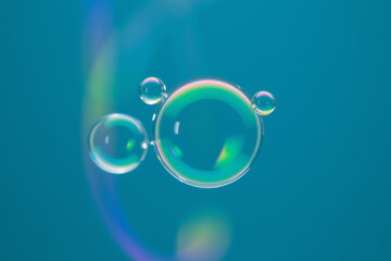 Vibrant soap bubbles floating on a serene blue background with rainbow reflections