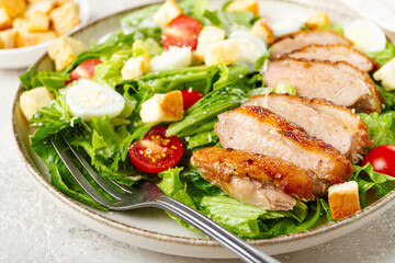 Caesar salad, with duck breast, on a light plate, on a light background, homemade, no people,
