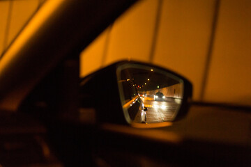 The side mirror reflects the mesmerizing scenery of a nighttime tunnel, illuminating the dark surroundings while driving