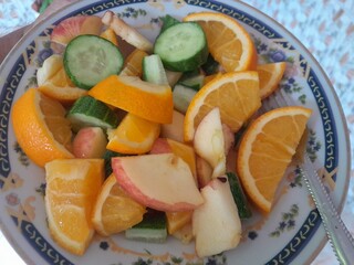 Vegetarian fruits mix salad with ingredients, slices of apple, orange, and cucumber.  