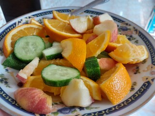 Vegetarian fruits mix salad with ingredients, slices of apple, orange, and cucumber.  