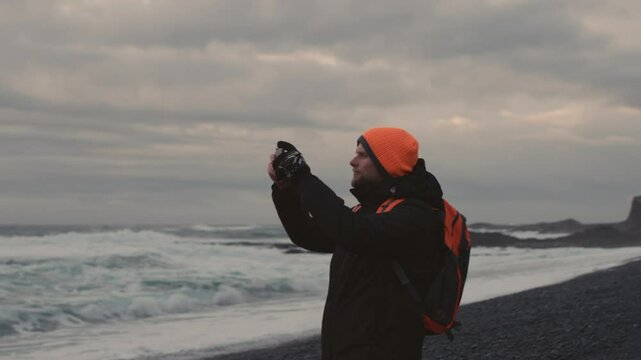 Man Exploring and Photographing Iceland&rsquo;s Black Sand Beach