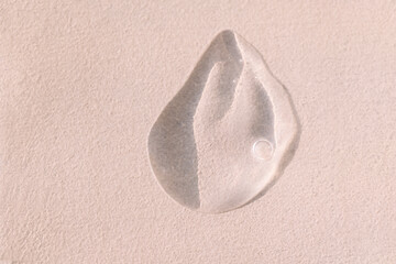 Obraz premium Close-up of a transparent gel smear with bubbles. Cosmetic products. A drop of serum or essence on a textured background. Bright sunlight.