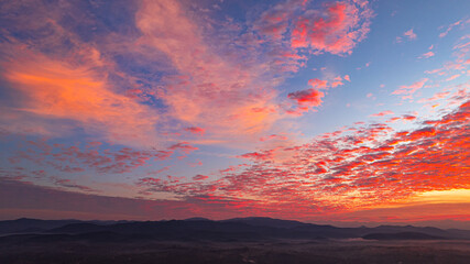 A breathtaking sunrise illuminates a small village nestled among lush green fields and karst...