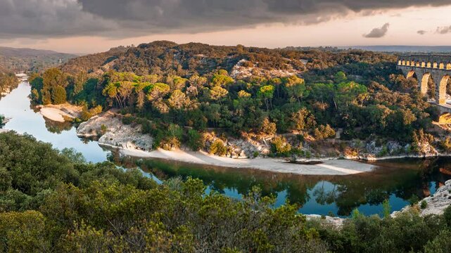 Pont du Gard, ancient Roman aqueduct bridge, elevated panoramic view, river bend and arches, early morning golden light, Gorges du Gardon, natural landscape, UNESCO Biosphere Reserve, Provence, France