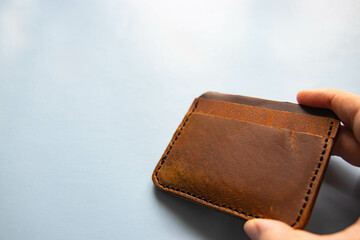 Brown handmade card holder in vintage style close-up. The credit card wallet is made of cowhide leather, stitched with waxed thread. Young craftsman makes unique things.